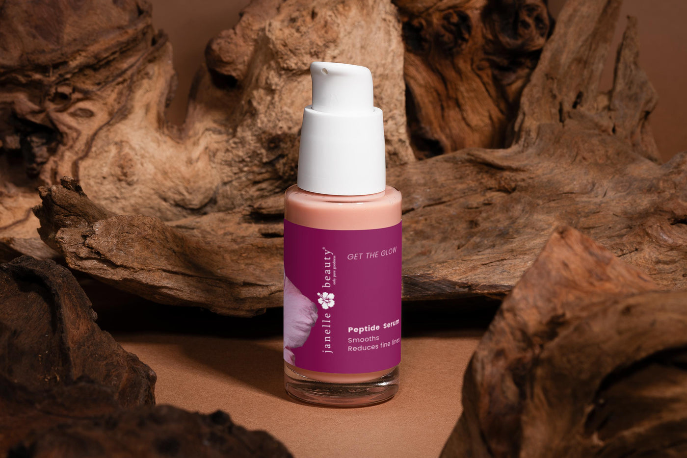 Skincare bottle with pink label on a brown background with natural elements